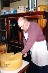 Jim Marilley cuts cheddar cheese at family general store, Croghan